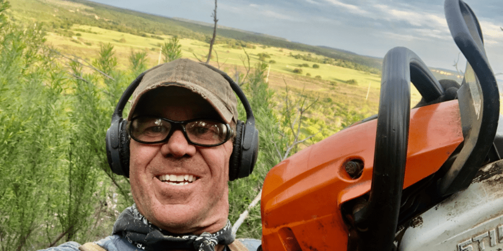 A man wearing headphones and holding an orange saw.