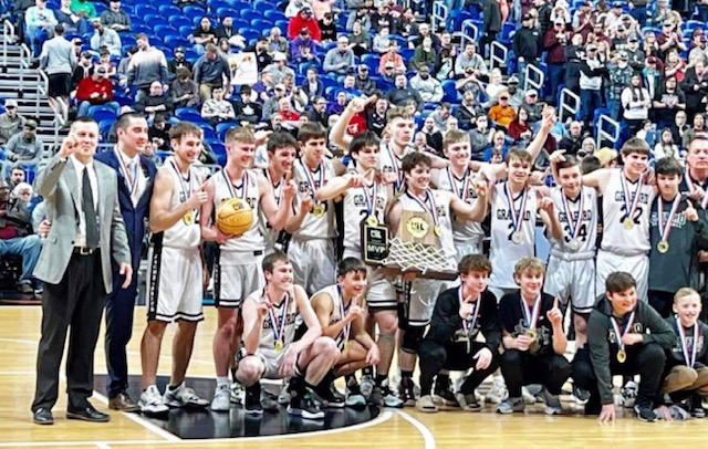 A group of boys holding up their basketball trophies.