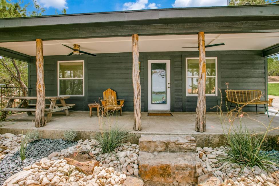 A porch with chairs and tables on the side of it.