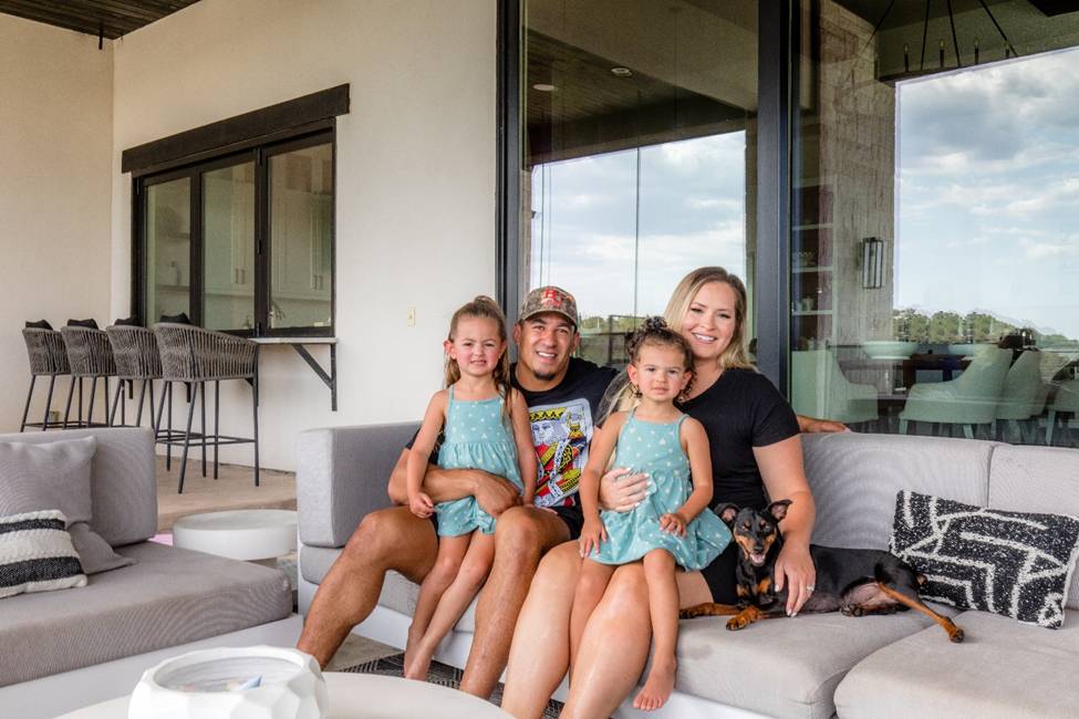 A family sitting on the couch in front of a window.