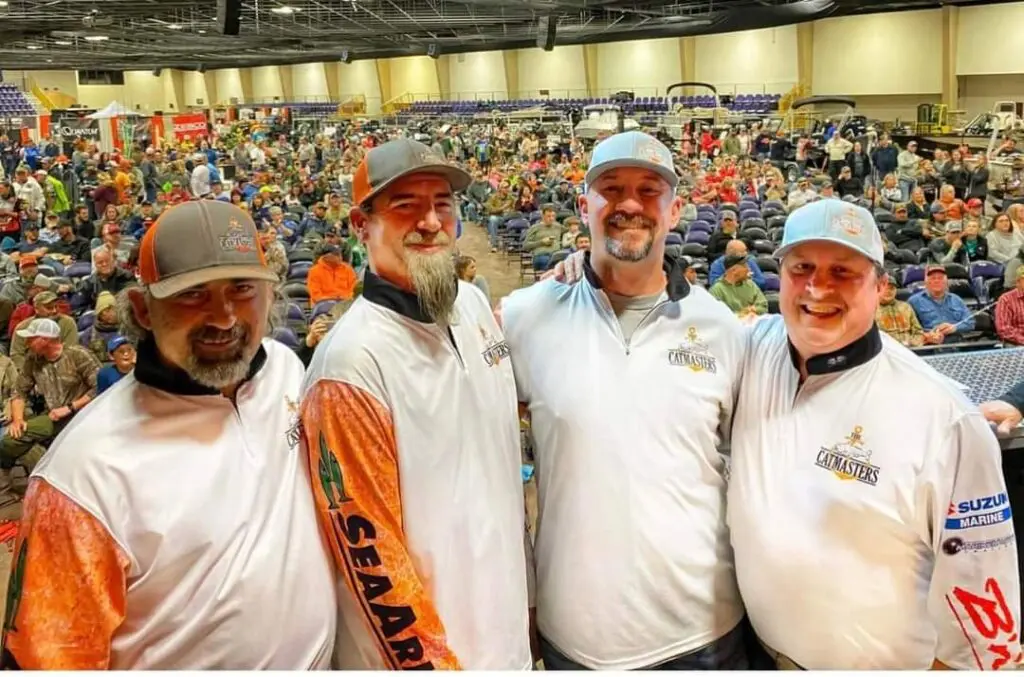 Four men in white shirts and hats are posing for a picture.