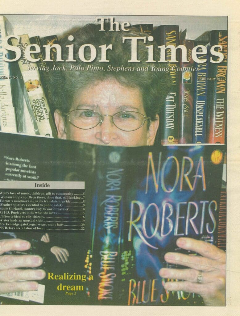 Person reading a Nora Roberts book with bookshelves in the background.