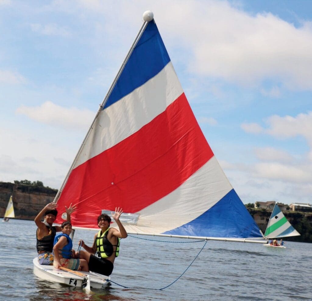 Two people sailing a boat with a colorful triangular sail.