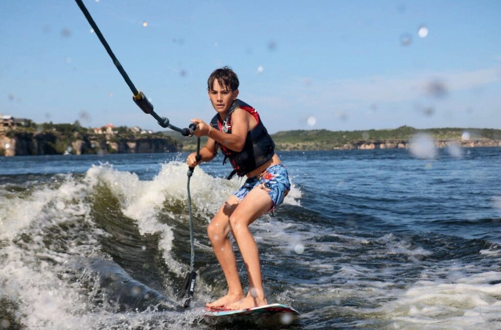 Person wakeboarding on a sunny day with splashing water.