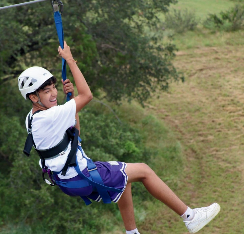 Child enjoying a zipline ride in an outdoor setting.