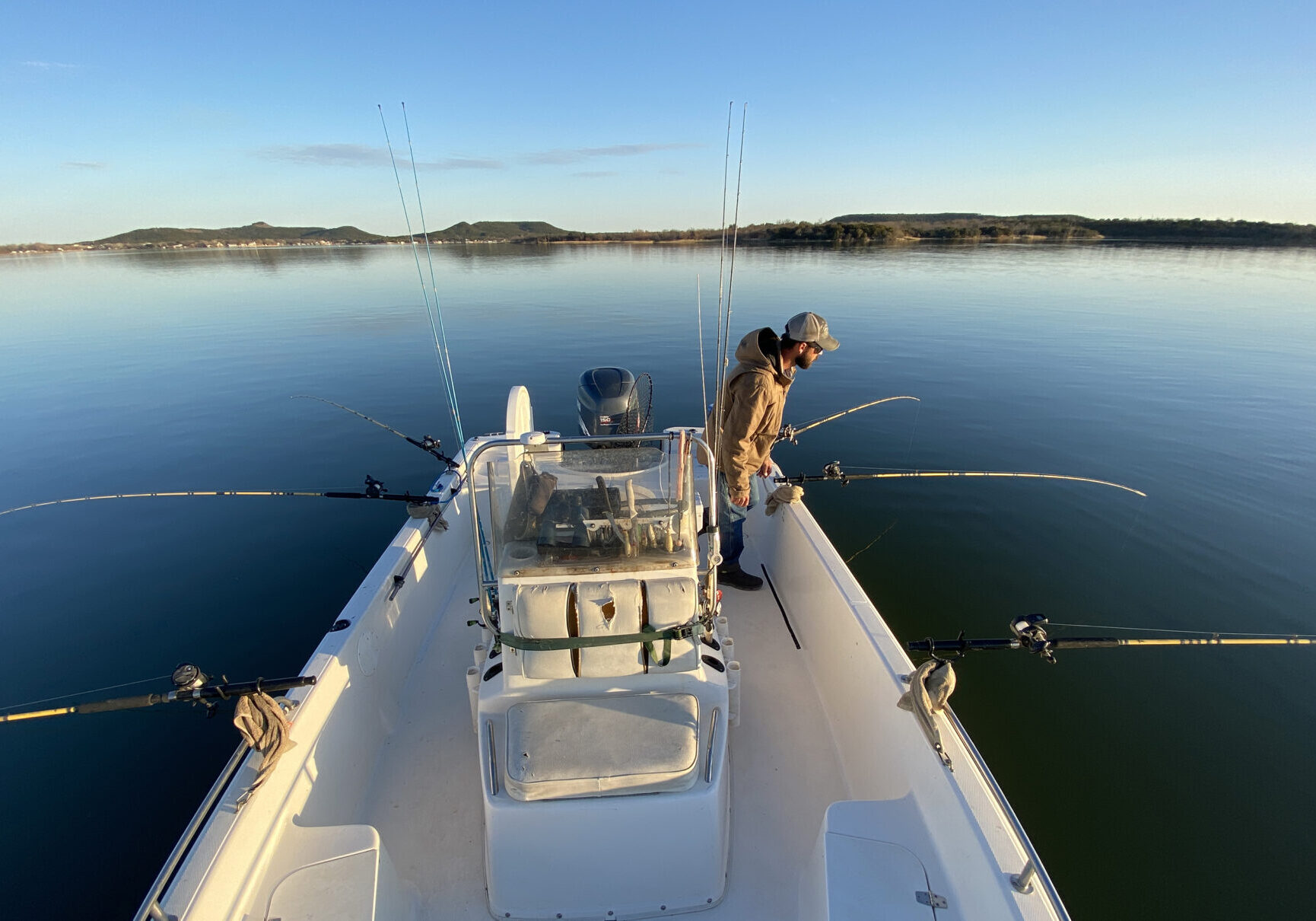 A man standing on the bow of a boat in water.