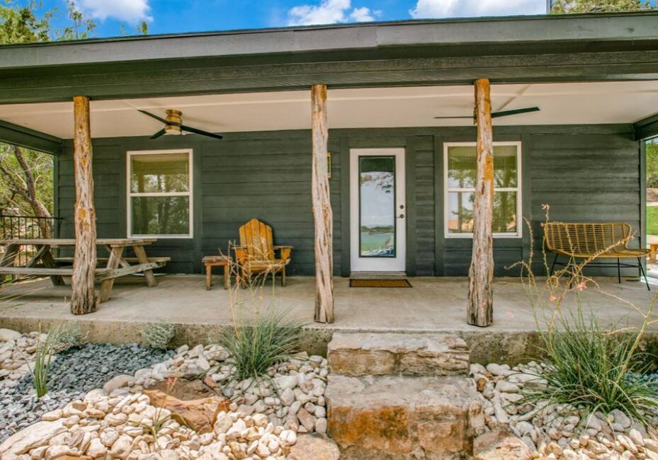 A porch with chairs and tables on the side of it.