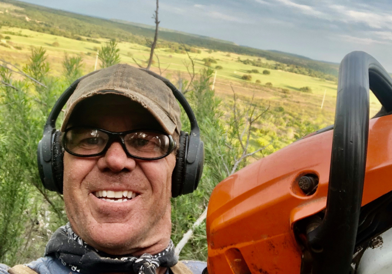 A man wearing headphones and holding an orange saw.