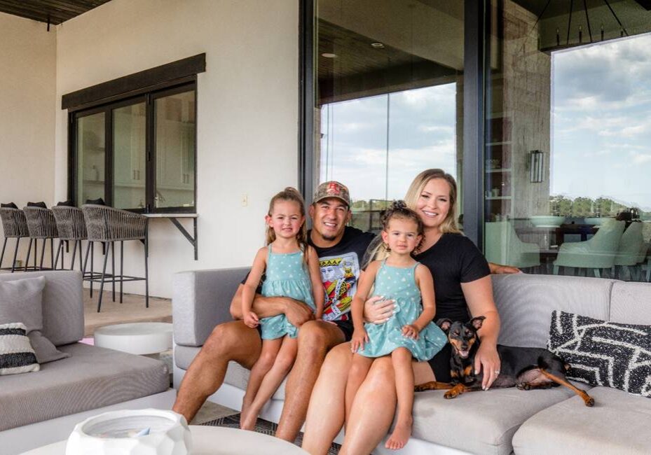 A family sitting on the couch in front of a window.