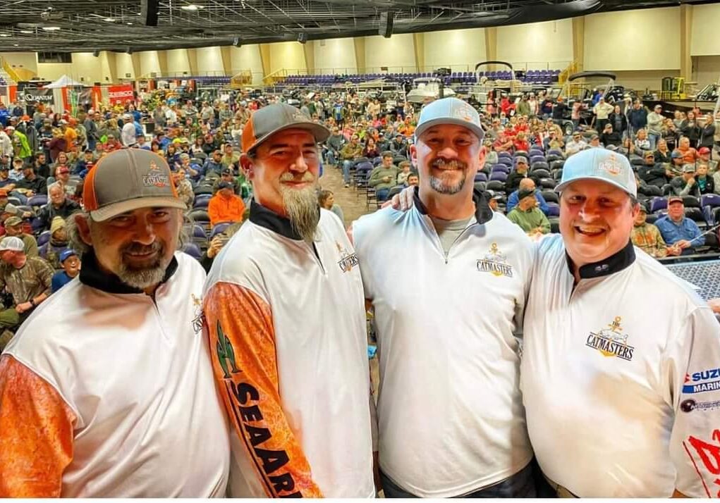 Four men in white shirts and hats are posing for a picture.